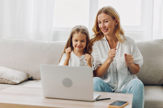 Mother and daughter bonding on the couch while exploring an educational program on the laptop together