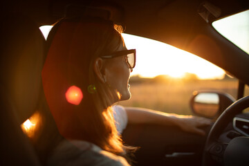 Happy young woman driving down country road looking out her window smiling feeling a sense of freedom 