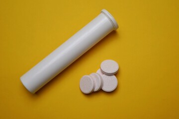 Effervescent Tablets with White Bottle on yellow Background Surface