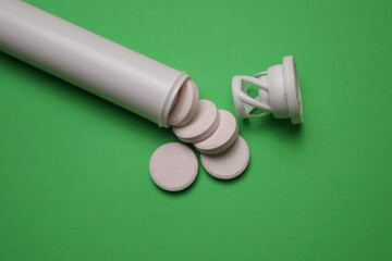 Effervescent Tablets with White Bottle on green Background Surface