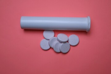 Effervescent Tablets with White Bottle on Pink Background Surface