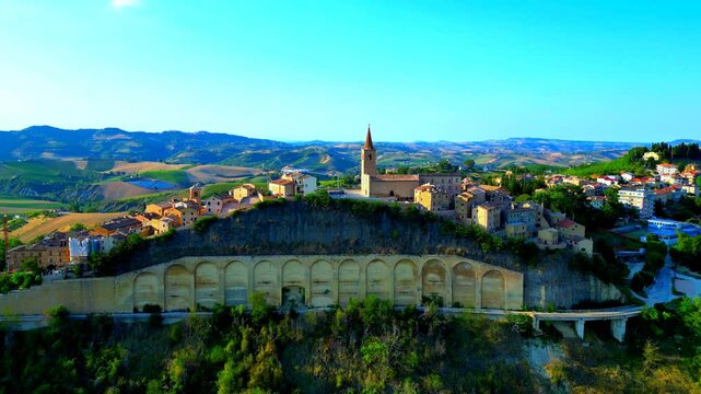 Amazing aerial pedestal up tilt down shot from Castignano (AP), drone rising to capture the full height of the particular town centre with arched walls, extending to the vision of sumptuous hillscapes