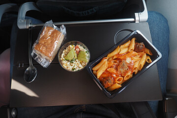 Airplane Meal Featuring Pasta with Bread Roll and Creamy Vegetable Salad
