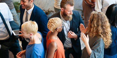 Diverse group of people in business attire networking at an event. Engaged in conversation, sharing ideas, and building connections in a professional setting. Diverse people talking together.