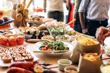 A table filled with a variety of food, including salads, pastries, and chips. The food spread includes fresh salads, delicious pastries, and crispy chips. Dinner buffet with international food.