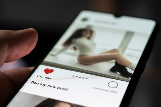 Man giving a like to photo on social media or swiping on online dating app. Finger pushing heart icon on screen in smartphone application. Friend, follower or fan liking picture of a beautiful woman.