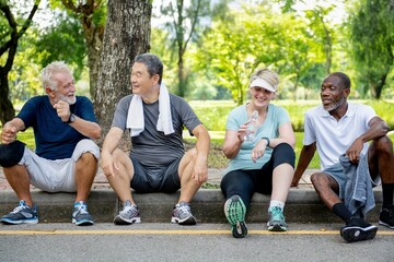 Fototapeta premium Group of diverse seniors people rest after exercise in park. Senior diverse group of people outdoor fitness activity, healthy lifestyle. Group of senior friends rest in park, healthy fitness exercise
