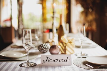 Elegant table with Reserved sign, wine glasses, and festive decor. Reserved table for special occasions,and dining event. Reserved sign on elegant festive dining table for special guest