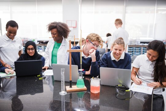Diverse students and teacher in a science lab, using laptops and lab equipment. Engaged in learning, experimenting, and collaborating in a classroom setting. Diverse students in science class.