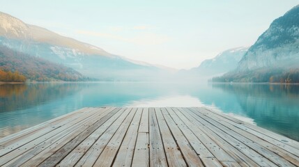 A wooden deck extends over a peaceful mountain lake, capturing the serene beauty of surrounding mist-covered mountains during early morning