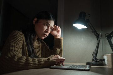 stressed woman headache while working with laptop at night....