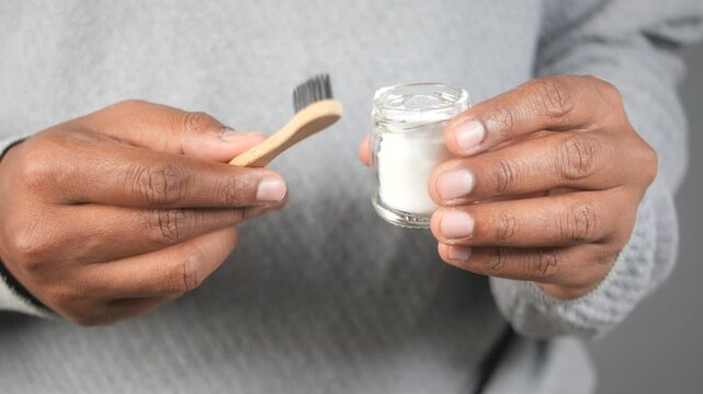 holding a jar of baking soda, a bamboo toothbrush