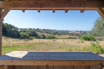 Fototapeta premium Serene Landscape View from a Wooden Shelter Showcasing Rolling Hills and Lush Greenery under Clear Blue Sky in a Rustic Natural Setting