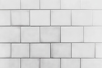 A clean, minimalist white tiled wall featuring rectangular tiles arranged in a classic pattern.