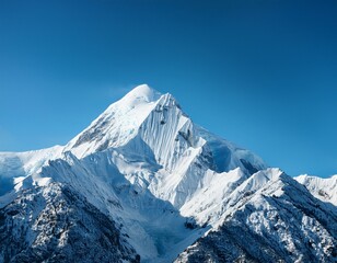 Fototapeta premium Majestic Mountain Peak: A majestic snow-capped mountain peak reaches for the clear blue sky, its sharp edges and rugged slopes a testament to the power of nature.