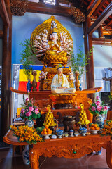 figurine of golden Shiva and white Buddha on an altar decorated with fresh flowers inside a...
