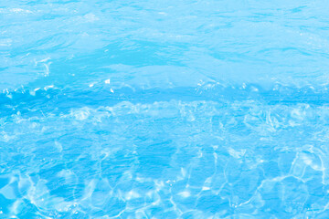 Blue water with ripples on the surface. Defocus blurred transparent blue colored clear calm water surface texture with splashes and bubbles. Water waves with shining pattern texture background.