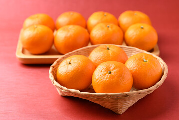 Mandarin tangerine orange fruit in basket on red background, Lucky food in Lunar New Year or Chinese New Year