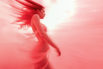 A woman with flowing red hair is captured in motion against a vivid, swirling red background. Her graceful posture and the ethereal setting create a dreamlike atmosphere.