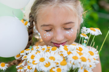 blonde little girl holds a bouquet of daisies and balloons, summer