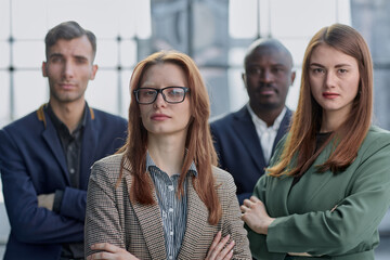 Business people stand with each other in a conference room with their arms crossed