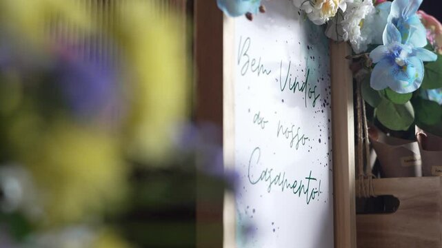 Artistic wedding welcome sign reading "Bem-Vindos ao nosso Casamento" adorned with flowers