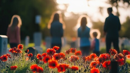 A family in silhouette visits a war cemetery, with red poppies in the foreground at sunset