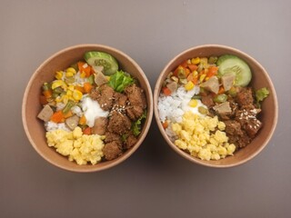Rice box with meat side dishes, scrambled eggs, meatballs and sweet corn.