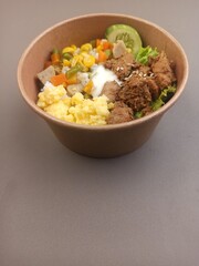 Rice box with meat side dishes, scrambled eggs, meatballs and sweet corn.