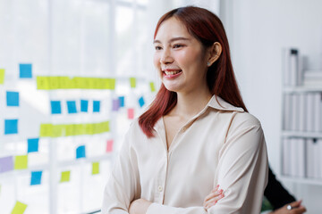 Business female employee with many conflicting priorities arranging sticky notes commenting and...