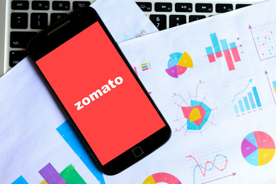 Zomato food ordering app logo on smartphone with financial chart and graph concept of stock market Quarter result share and stocks of Zomato company.
