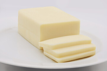 STANDARD BAR CHEESE WITH CUT SLICES WITH PLATE ON WHITE BACKGROUND ISOLATED