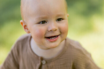 Baby boy walks barefoot on the lawn in summer, children's muslin suit