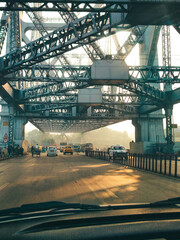Naklejka premium Morning Traffic Under Howrah Bridge Steel Structure in Kolkata, India Urban Commute Scene