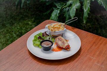 Beef Ham And Melted Cheese Topped Dish, Served With French Fries, Fresh Salad, And Mushroom Sauce On A White Plate.