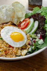 Fried Rice With Sunny Side Up Egg, Fresh Vegetables, And Crackers, Served In A White Bowl On A Wooden Table.