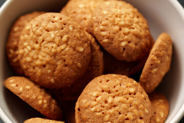 Freshly baked sesame cookies arranged in a white bowl ready for snacking or serving during afternoon tea