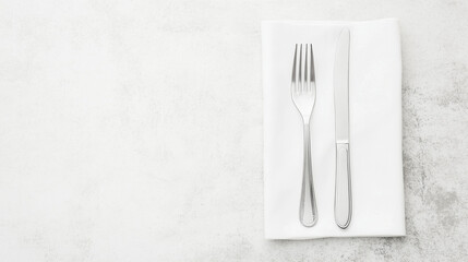 Elegant Place Setting: A minimalist overhead shot featuring a knife and fork neatly arranged on a crisp white napkin, perfect for restaurant menus, culinary blogs, or elegant event invitations. 