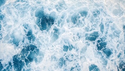 Aerial view of ocean waves, white foam, blue water texture.