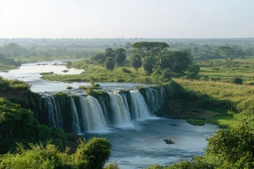 Selbstklebende Fototapeten Scenic waterfall cascading into serene river in lush green landscape © kardaska