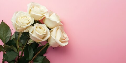 Fototapeta premium White rose bouquet arranged elegantly on a smooth pink backdrop with lush green leaves, providing ample space for text and creative visuals.