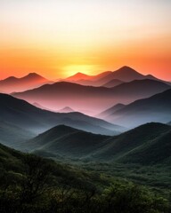 Obraz premium A breathtaking sunset over misty mountains, showcasing layered hills and a vibrant sky painted in hues of orange and purple.