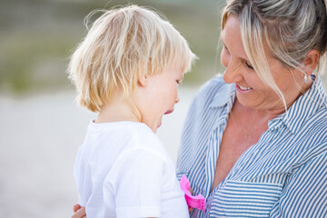 Fototapeta premium Mother and toddler son embracing on the sand of Gold Coast beach