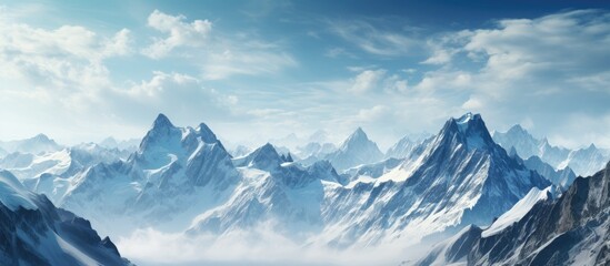 Obraz premium Snow-capped mountain peaks rise sharply under a bright blue sky, with wispy clouds spread across the tranquil alpine landscape.