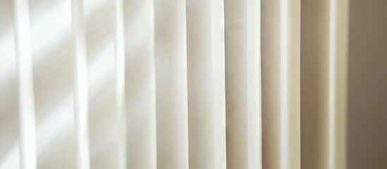 Fototapeta premium Vertical white blinds casting soft shadows as sunlight filters through creating a serene ambience in a light-filled room with neutral tones.