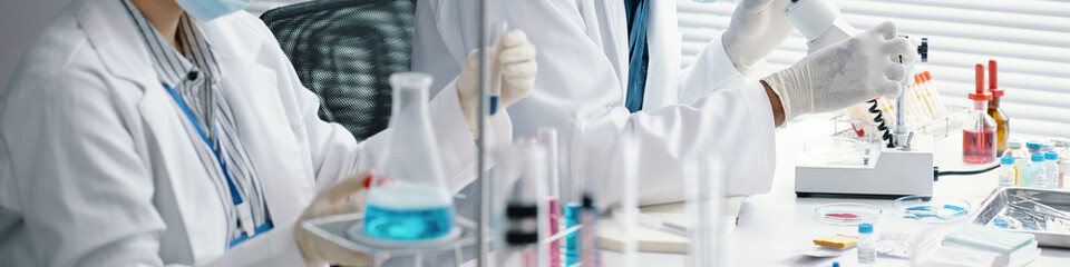 Researchers conducting scientific experiments, wearing lab coats and gloves, handling test tubes and beakers in a modern laboratory environment with various lab equipment
