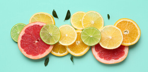 Many different cut citrus fruits on turquoise background, top view