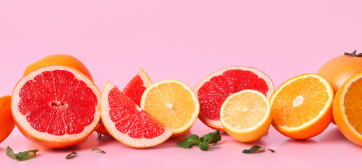 Many different cut citrus fruits on pink background