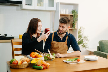 Discover a joyful couple preparing fresh vegetables, embracing healthy eating and teamwork in a vibrant kitchen