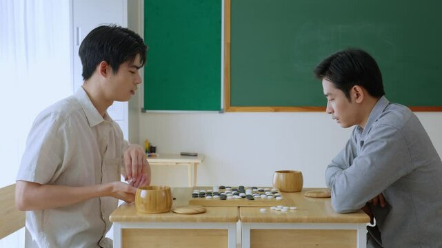 Asian young men playing board game Go during competition in community. 